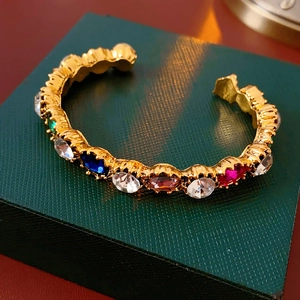 Close-up of vintage gold cuff bracelet featuring vibrant multi-colored crystal inlays