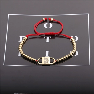 Detail of red rope bracelet with gold beads and heart zircon lock charm pendant