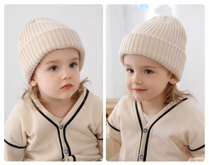 Close-up of a warm beige striped knitted beanie for toddlers in a soft indoor setting.