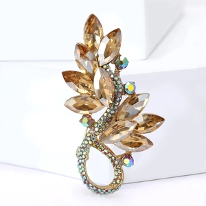 Detailed close-up of golden leaf brooch with amber gems and iridescent rhinestones