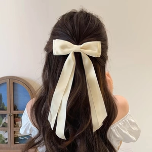 Cream white double layer satin bow hair clip with long ribbons worn by a female model