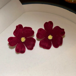 Detail shot of vintage red velvet flower earrings with golden floral stamens and matte finish