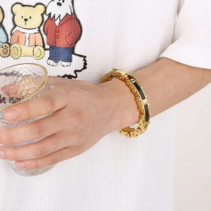 Close-up of golden motorcycle chain bracelet with black carbon fiber inlay for men