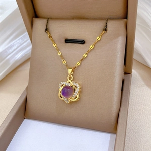 Detail shot of a luxury gold necklace with purple stone and diamonds in a gift box