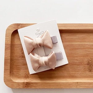 Close-up of pink fabric ribbon bow hair clips on a wooden tray for little girls