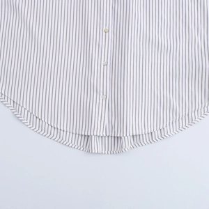 Détail de l'ourlet arrondi d'une chemise à rayures grises avec boutons en nacre