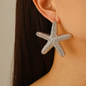 Oversized silver starfish stud earrings with textured finish on a fashion model