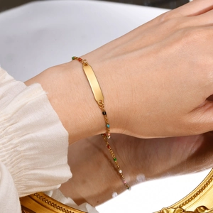 Detailed shot of golden stainless steel cross plate bracelet with colorful beads on wrist