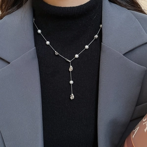Detail of silver Y-shaped pearl necklace with irregular metal pendants on model