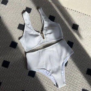 Two-piece white ribbed high waist bikini with a stylish gold V-shaped metal accessory