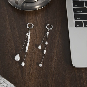 Classic stainless steel pearl tassel earrings on dark wood office desk background