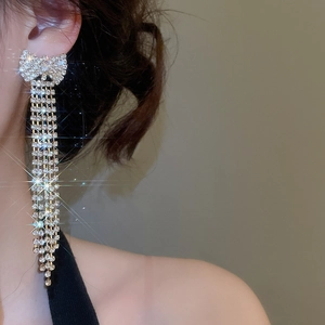 Detail of elegant silver bow earrings with long shimmering five-row rhinestone tassels