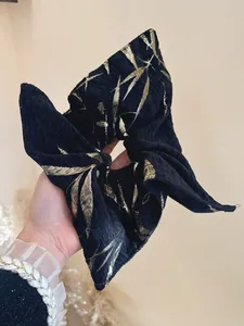 Detail of black jacquard hair scrunchie with golden bamboo leaf patterns and texture