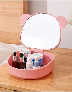 Pink bear-shaped folding makeup mirror with storage box on a wooden bedside table