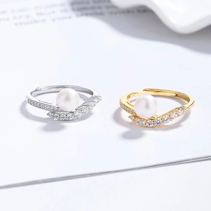 Detailed view of white pearl rings with V-shape zircon pave band in silver and gold colors