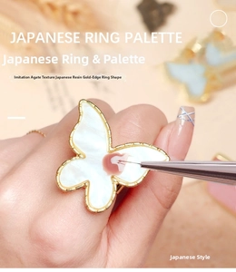 Macro view of butterfly resin nail art palette ring with gold rim for mixing polish