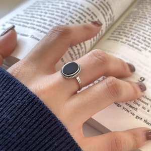 Close-up of vintage 925 silver ring with black agate stone worn on a finger over a book