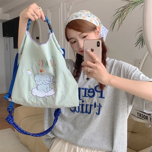 Macro shot of cute elephant embroidery and braided blue rope strap on green tote bag