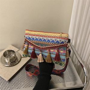 Close-up of bohemian shoulder bag with colorful geometric embroidery and thick tassels