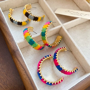 Detail of three pairs of bohemian colorful knit cord C-shape hoop earrings in a wooden tray