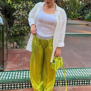 Detail of shimmering green sequin wide-leg pants styled with a white shirt and crop top