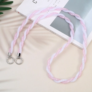 Pink and white braided crossbody phone strap with silver metallic rings on a magazine