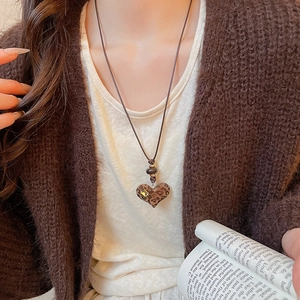 Close-up of leopard print heart necklace with sparkling crystal worn by a model
