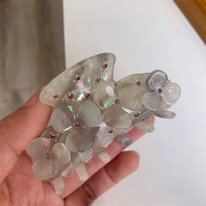 Detail of grey acetate flower hair claw with shimmering finish and pink rhinestones