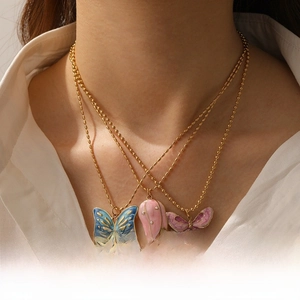 Detailed view of layered gold chain necklaces with blue butterfly and floral pendants