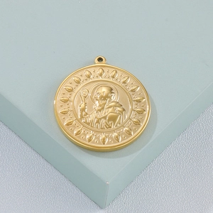 Detailed close-up of golden Saint Benedict religious relief pendant with floral borders