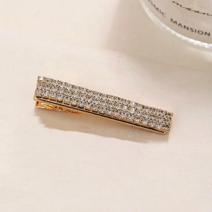 Minimalist gold hair clip featuring four rows of sparkling rhinestones in a macro side view