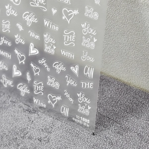 Makroaufnahme von weißen handgezeichneten Buchstaben-Nagelstickern mit Love-Wörtern