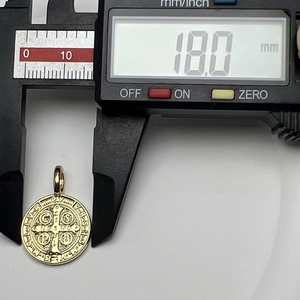 Close-up of 18mm golden Virgin of Guadalupe pendant measured by digital caliper
