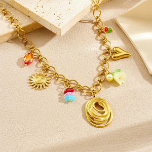 Golden necklace with sun face, heart and acrylic lily charms on stone background