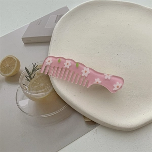 Pink acrylic flower hair comb hair clip detail on a decorative tray with aesthetic background