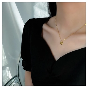 Minimalist gold heart pendant necklace shown on a model neck with an elegant black outfit