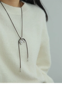 Close-up of minimalist diamond heart pendant necklace on white sweater