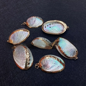 Macro view of seven natural abalone shell pendants with golden metal frames and iridescent finish