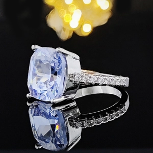 Exquisite silver ring with large blue cushion-cut gemstone and pavé accents on black background