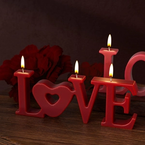 Detail view of heart-shaped O in red LOVE letter candles on a wooden table