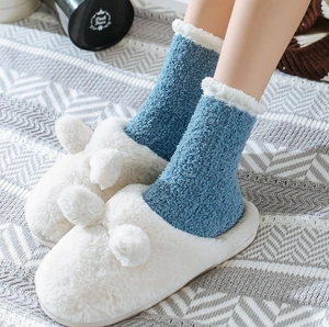Close-up of blue coral fleece socks with white faux fur trim and plush slippers
