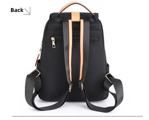 Detail view of the black nylon backpack back with orange contrast straps and anti-theft pocket