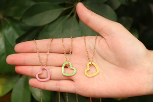 Set of three colorful heart pendant necklaces in pink, green, and yellow on gold chains