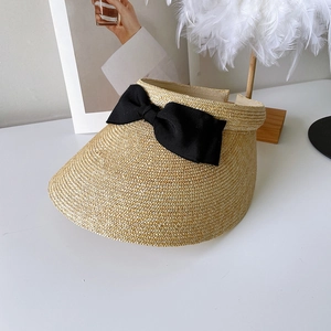 Detail of the woven straw visor texture and oversized black grosgrain ribbon bow