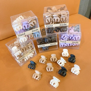 Close-up of colorful mini claw clips in transparent boxes on orange leather background