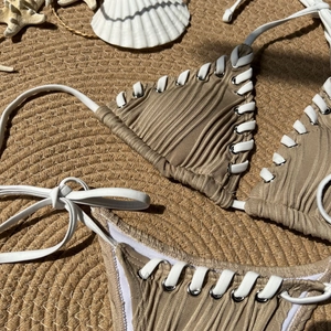 Detail of ribbed brown bikini with white side-tie laces and silver eyelet rings
