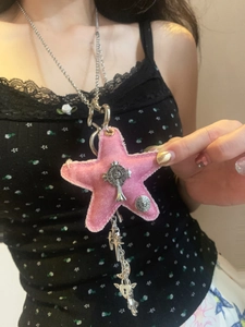 Close-up of pink denim star pendant with silver cross and heart charms on a chain