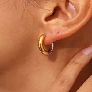 Detailed close-up of chunky two-tone gold and silver polished stainless steel hoop earrings