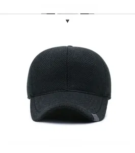 Detail of dark grey winter wool baseball cap featuring herringbone texture and metal emblem