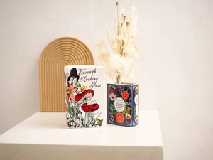 Macro shot of book-shaped ceramic vases featuring Alice in Wonderland and Secret Garden themes